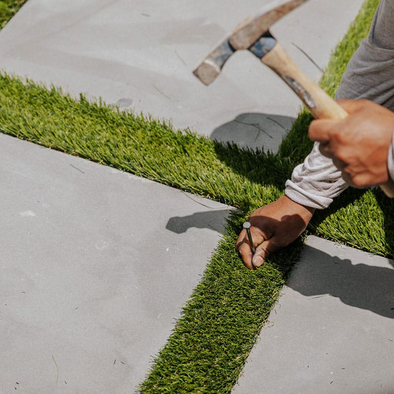 Securing the artificial grass between pavers